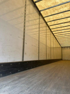Trailer interior showing empty cargo area with aluminum side rails and wooden floor in a Wabash van.