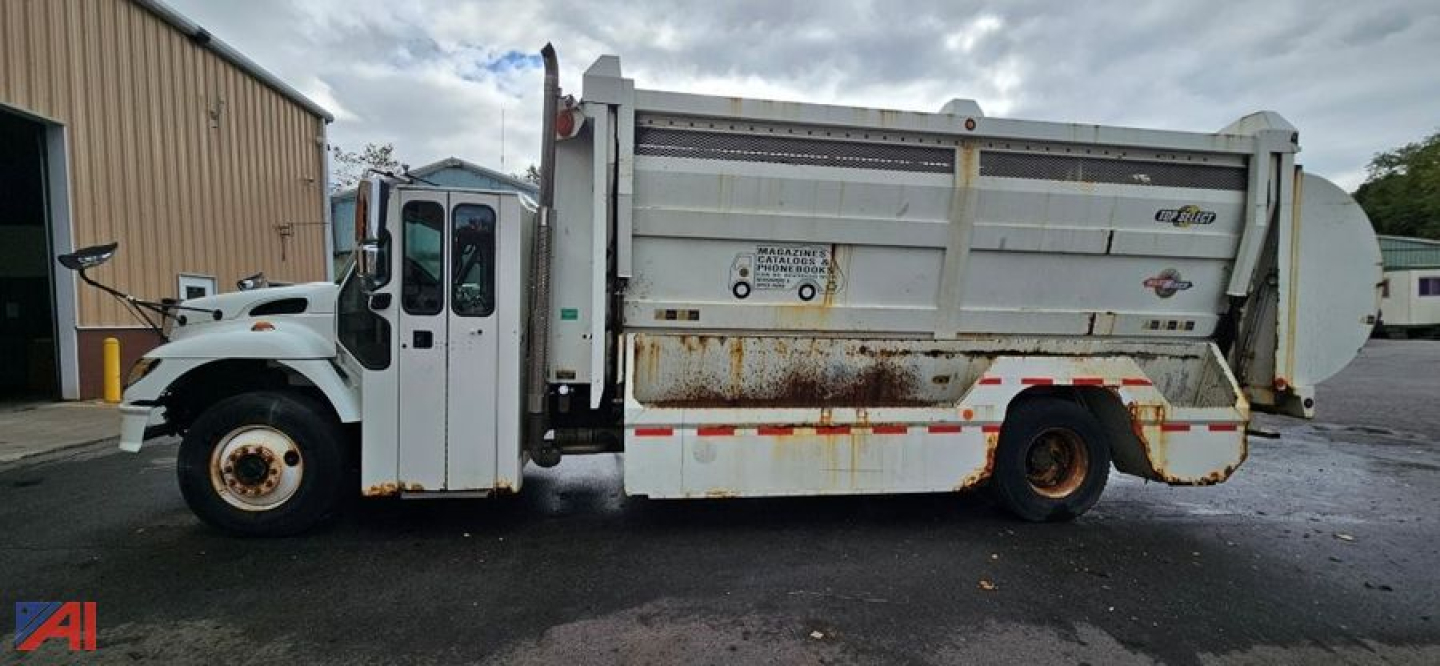 Truck side view of a 2007 International SA625 WorkStar dump truck showing side panels with rust and warning stickers, front cab, and large dump bed.