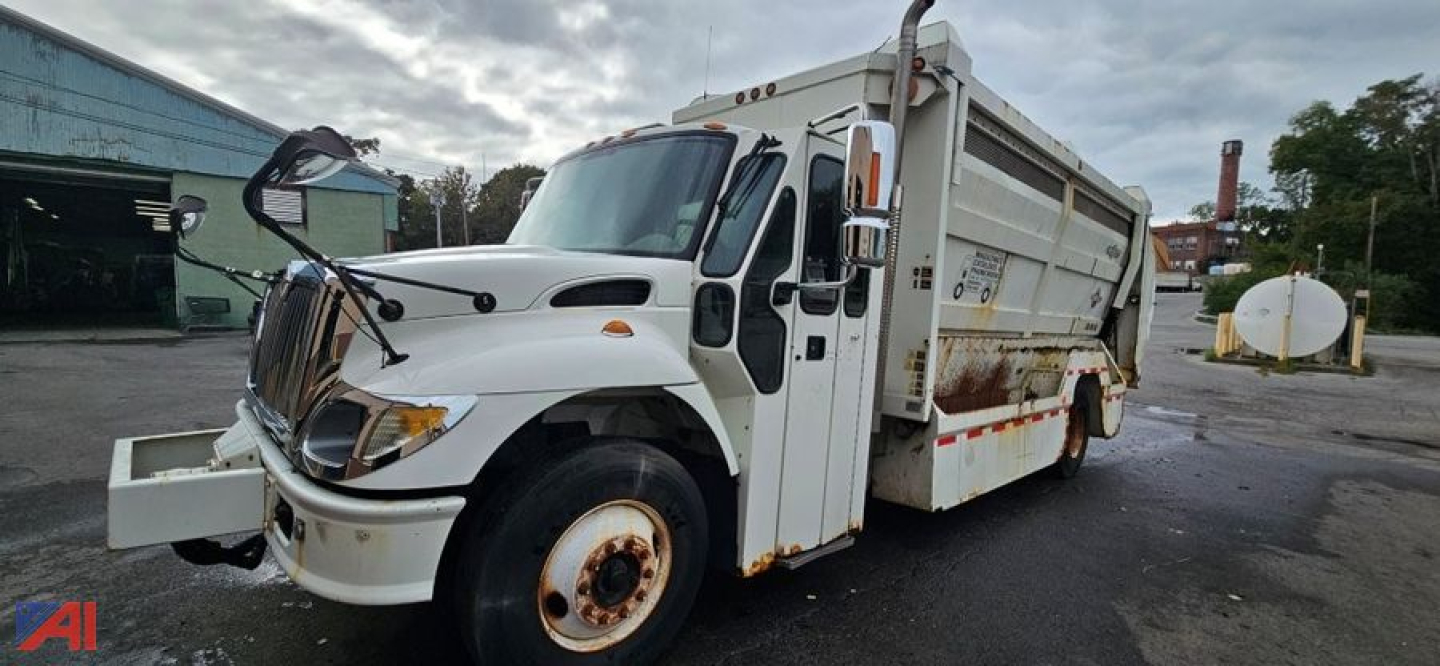 International SA625 WorkStar 7400 garbage truck side view showing cab and rear dump body with white paint and orange accents.