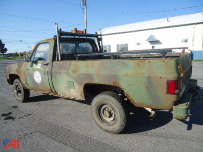 Military-style 1985 Chevrolet D30 pickup truck with rusted green body, 4x4, long bed, rear hitch, and winch area.