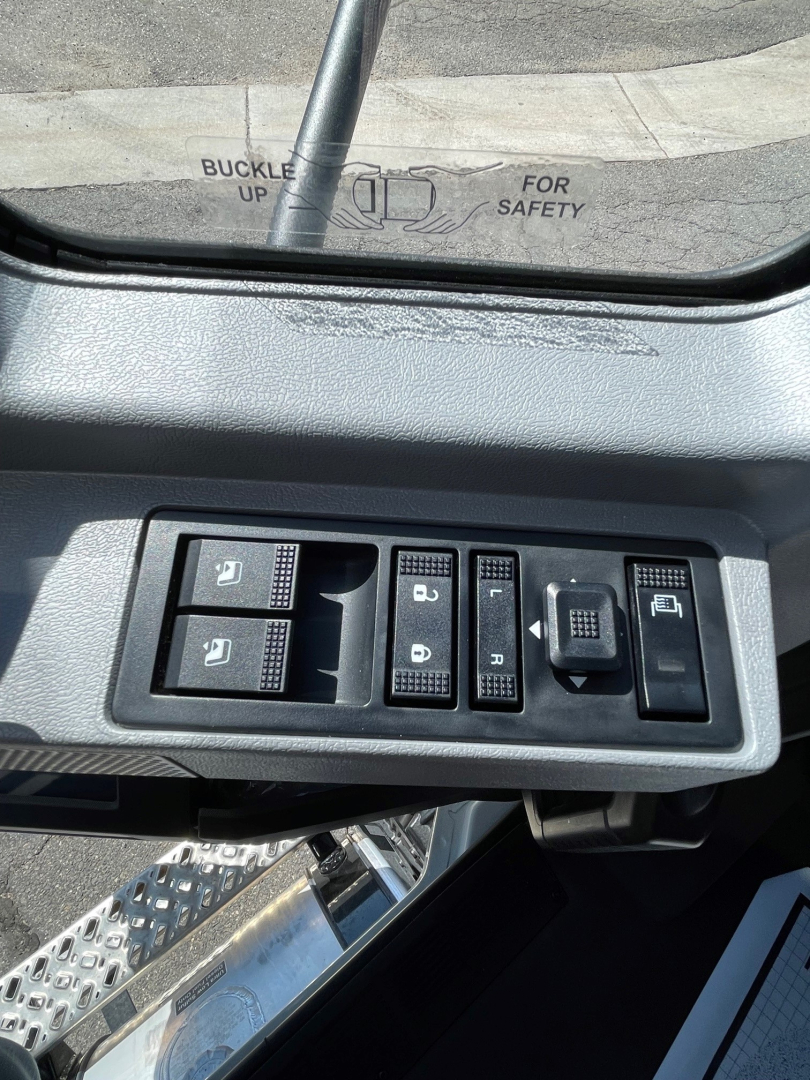 Dashboard controls and window switch panel inside a Mack MD6 cab with multiple switch buttons and a rear view mirror reflection