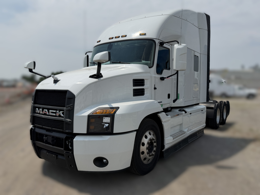 Truck: 2024 Mack AN64T70 conventional sleeper with white cab and raised sleeper, showing front grille with MACK logo and dual fuel tanks, three-axle configuration.