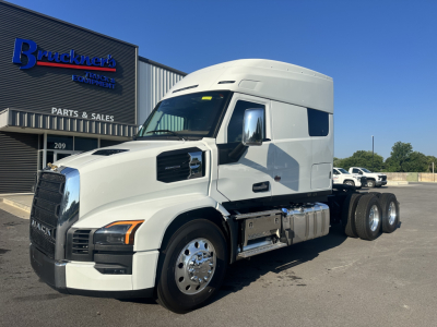 Mack PR64T76M conventional sleeper truck shown in white, side view with cab and dual rear axles, dealership building in background.