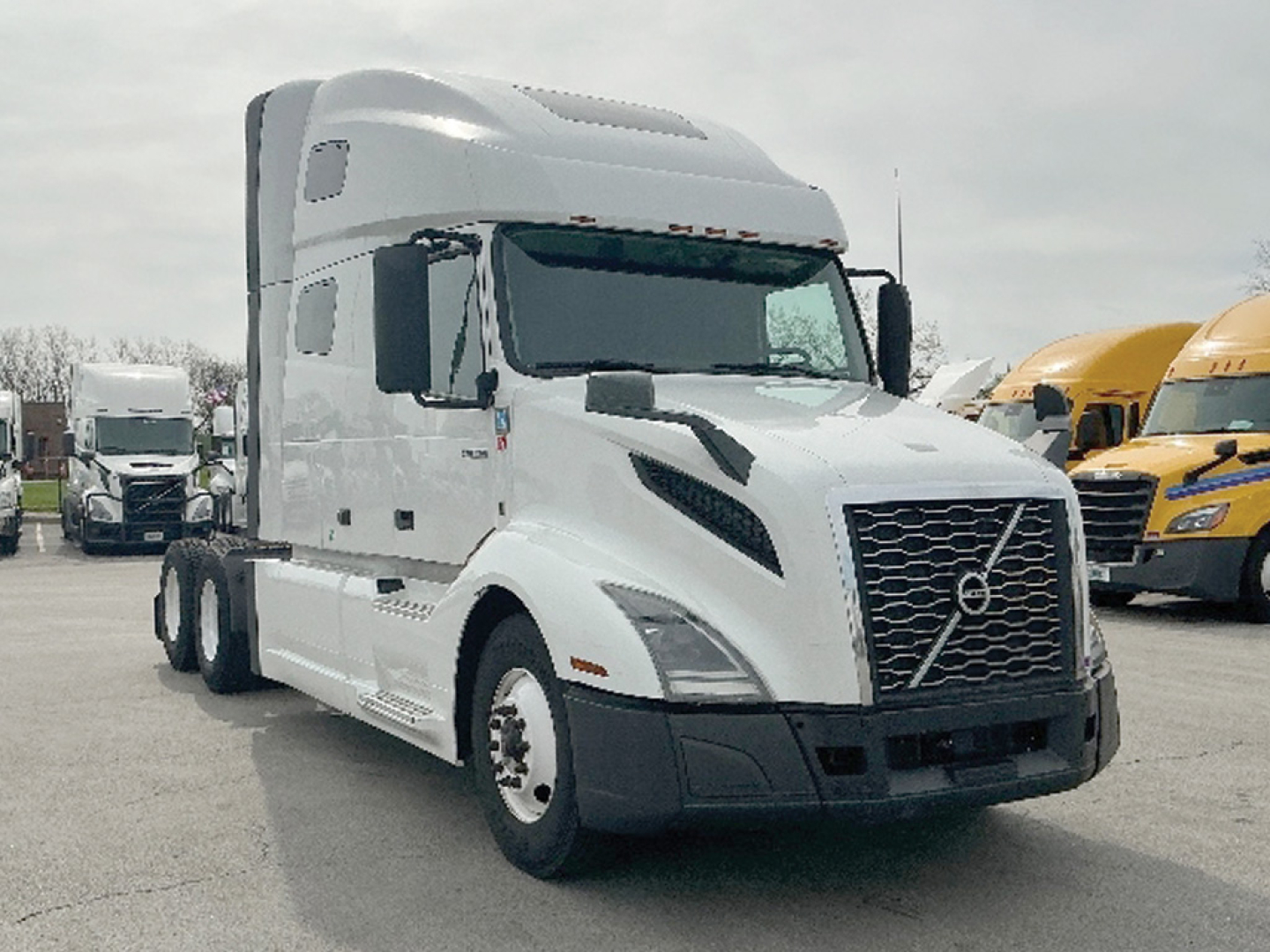 Volvo VNL 760 semi-truck in a parking lot with white cab, gray grille, and large aerodynamic mirrors.