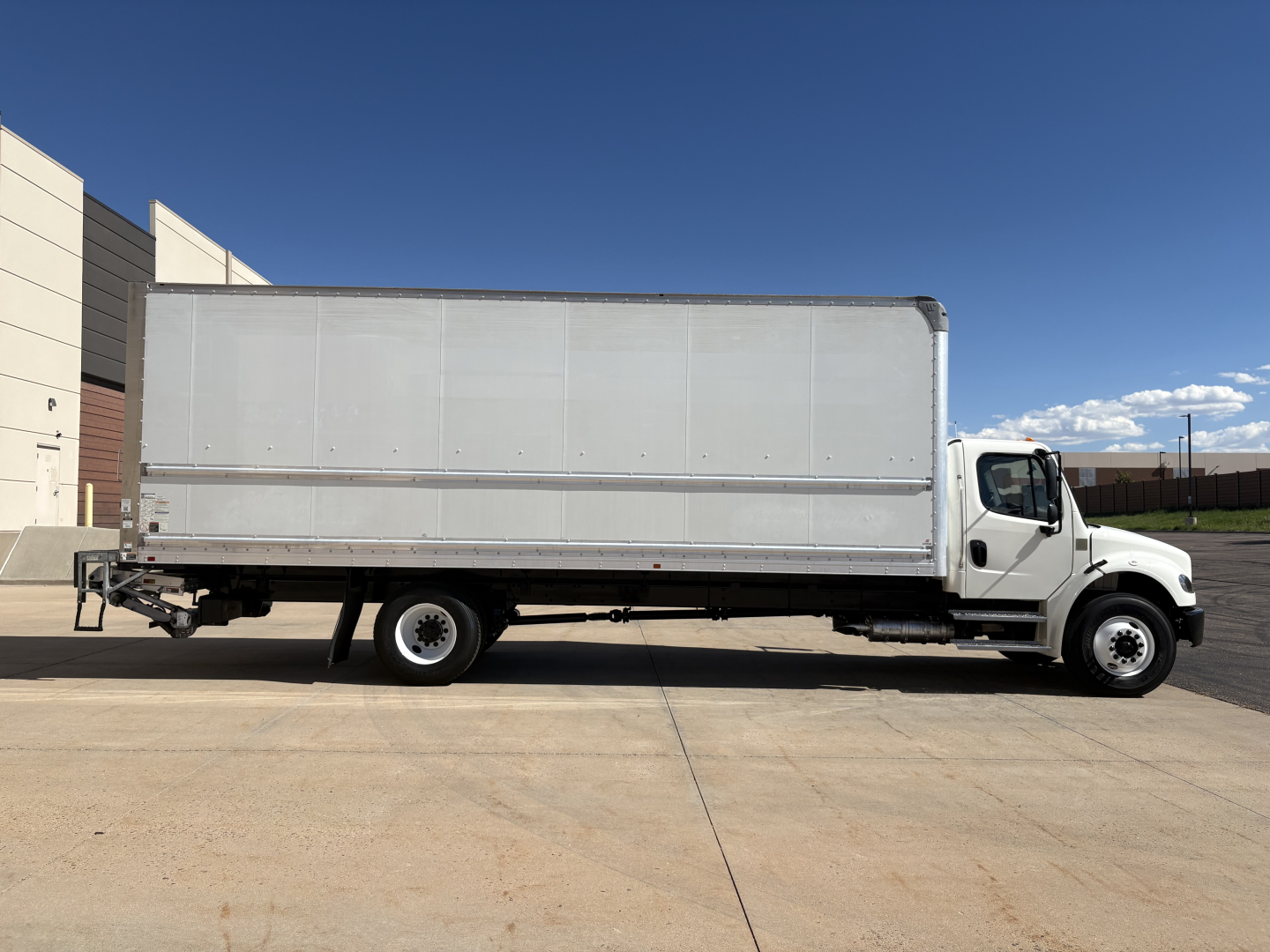 Freightliner M2-106 box truck side view showing long cargo box and cab with white exterior and no branding visible.