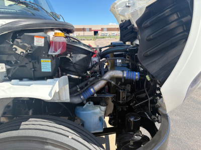 Front engine bay of a 2022 Freightliner M2-106 showing coolant reservoir, power steering reservoir, hoses, and various components in view.