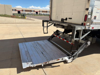 Freightliner M2-106 truck rear with fold-out aluminum liftgate and platform, view of the tail of a box truck from the passenger side, concrete ground.