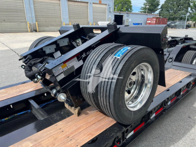 Trailer equipment showing XL Specialized XL22FA lowboy trailer wheel assembly and hitch with spare wheel and metal framing.