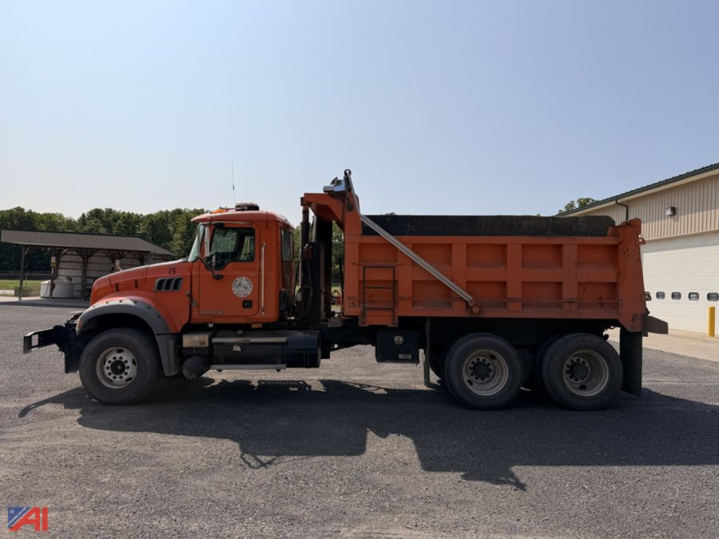 Dump truck with plow and wing in service showing side profile and orange cargo bed
