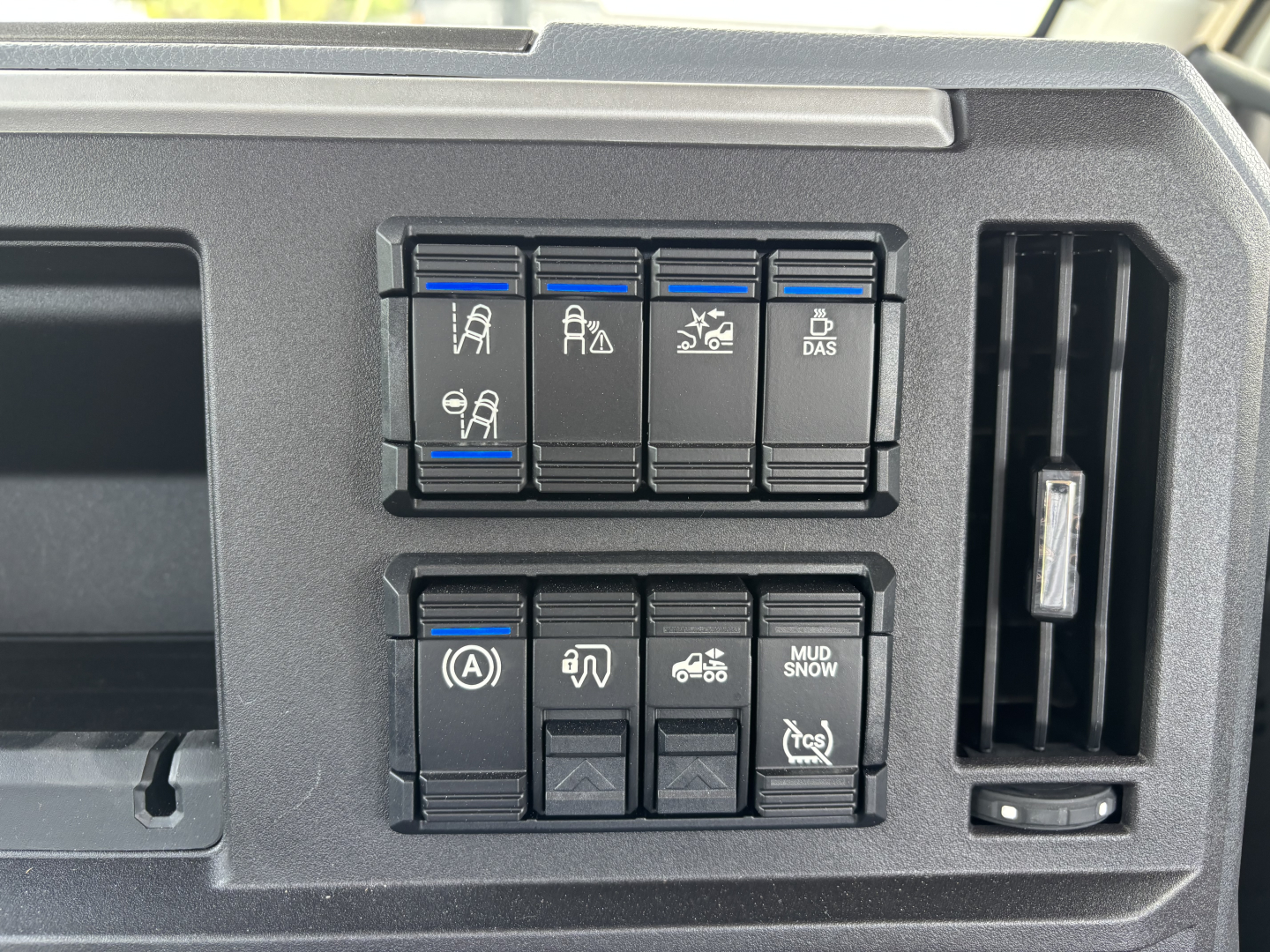 Dashboard switches and controls in a Mack AN64T truck cab showing multiple toggle buttons and a vertical vent.