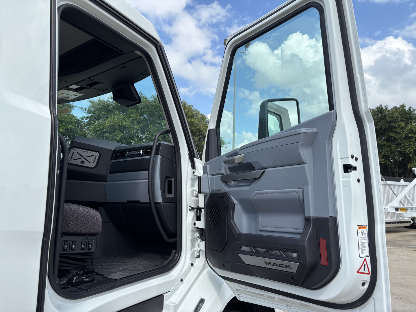 Truck cab interior and open door of a white Mack AN64T; visible text on door panel says 'MACK'.