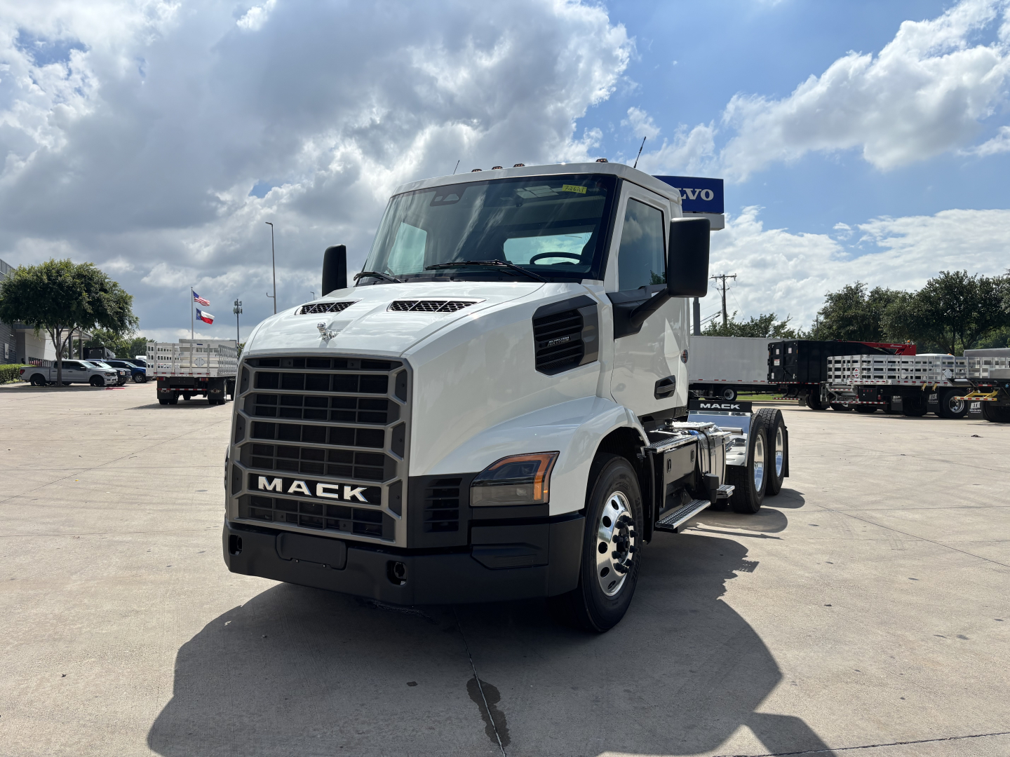 Mack AN64T conventional daycab truck front-left view with white cab and black grille, showing Mack emblem and VIN/stock notations not visible.