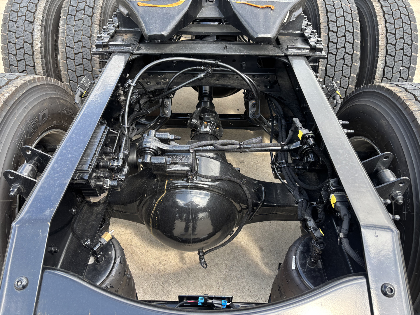 Rear view of a Mack AN64T chassis showing differential housing, axles, and suspension components under a Daycab truck.