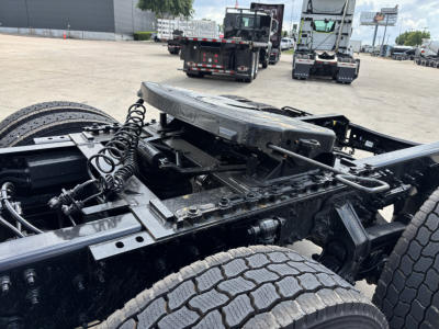 Chassis view of a Mack AN64T daycab truck showing the fifth wheel area, dual rear axles, and exposed frame with wiring and components.