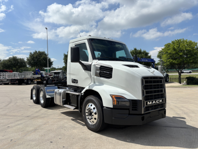 Mack AN64T conventional daycab truck in a dealership lot with white cab and black grille, side view showing 6-wheel configuration and front badge reading MACK