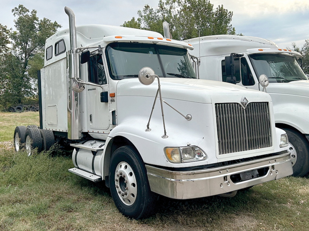 Truck cab showing large vertical grille, front bumper, and side mirrors. Visible text and features include International-style sleeper cab with chrome details, dual fuel tanks, and a white paint job.
