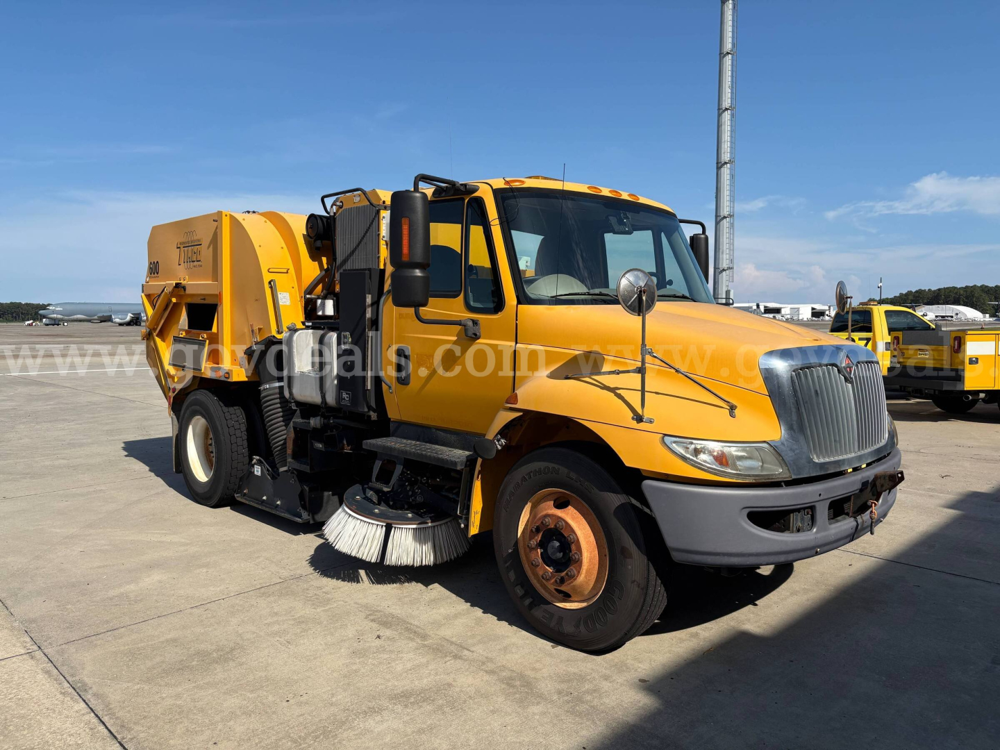 2012 International DuraStar street sweeper in yellow with side broom and rear water tank, front grille and headlights visible, VIN 1HTJTSKN8CJ536664.