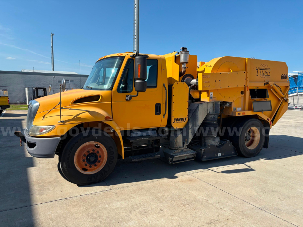 2012 International DuraStar street sweeper truck in yellow, side view showing front cab, cleaning unit, and debris hopper.