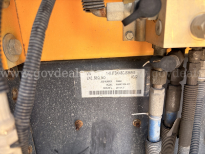 Label plate on International DuraStar showing VIN 1HTJTSKN8CJ536664, line SEQ no, model year, and date codes, with surrounding hydraulic hoses and metal panels.