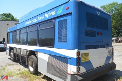 Bus rear view showing hybrid branding and spare tire area on Gillig Low Floor bus, side windows, blue and white livery, caution sticker, rear vents.