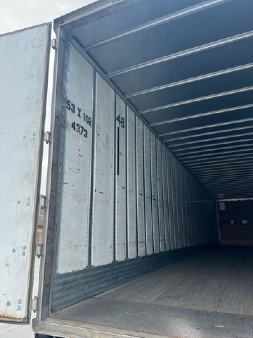 trailer van interior showing empty cargo area with ribbed metal sidewalls and open rear door