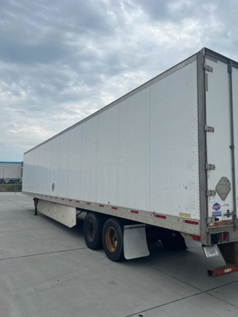 Utility van trailer showing long white box trailer with tandem rear axles and mud flaps.