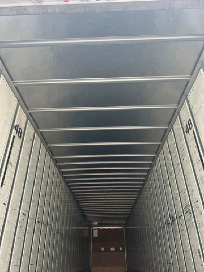 Van trailer interior cargo space with metal sidewalls and ceiling, long narrow perspective, numbered panels along walls.