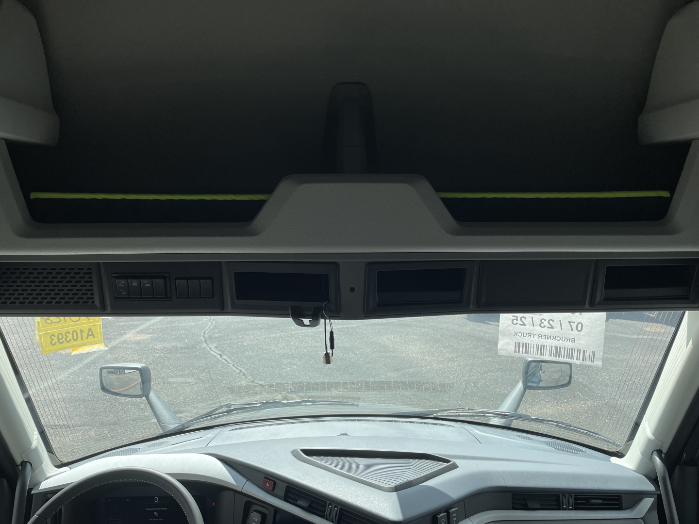 Truck cab interior windshield view of a Volvo VNL64T660 from driver seat. Dashboard, steering wheel, and rearview mirrors visible.