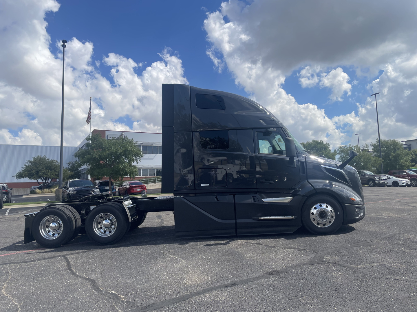Volvo VNL64T660 tractor unit side view showing sleeper cab and chrome wheels with six tires, black paint, no visible text.