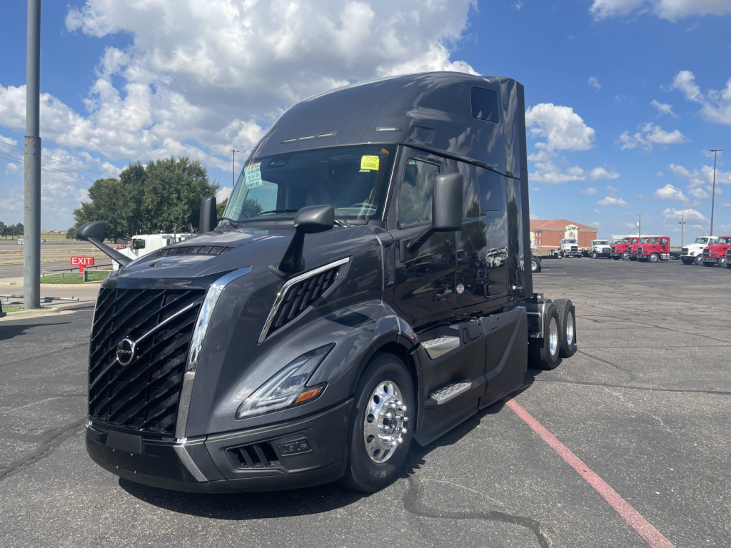 Volvo VNL64T660 truck in a dealership lot, black exterior, cab with large sleeper, front grille and headlights visible.