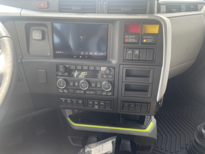 Volvo VNL64T660 cab interior showing center dash with touchscreen, climate controls, and various switches; visible warning/reminder panels and storage compartments.