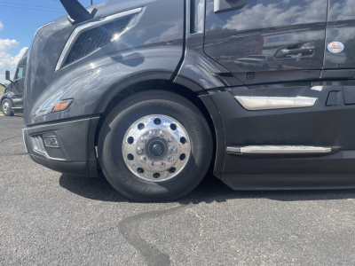 Volvo VNL64T660 front wheel showing chrome hub and tire with black fender and side chrome trim.