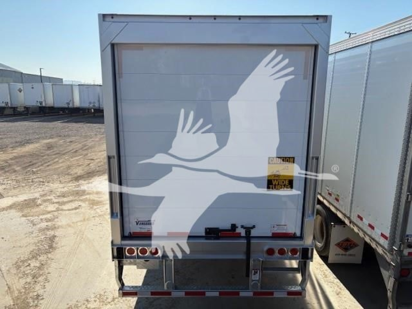 Reefer trailer rear showing doors, bumper, and warning label; no specific model text visible on the door; forklift-safe; generic trailer hardware.