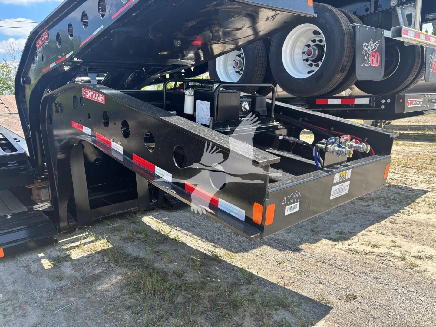 Fontaine Renegade N12 lowboy trailer with black steel frame, visible hydraulic components, spare wheels, and safety decals. Text visible includes 'FONTaine' on the side and warning/label stickers on the frame; also shows 'A' serial plate an