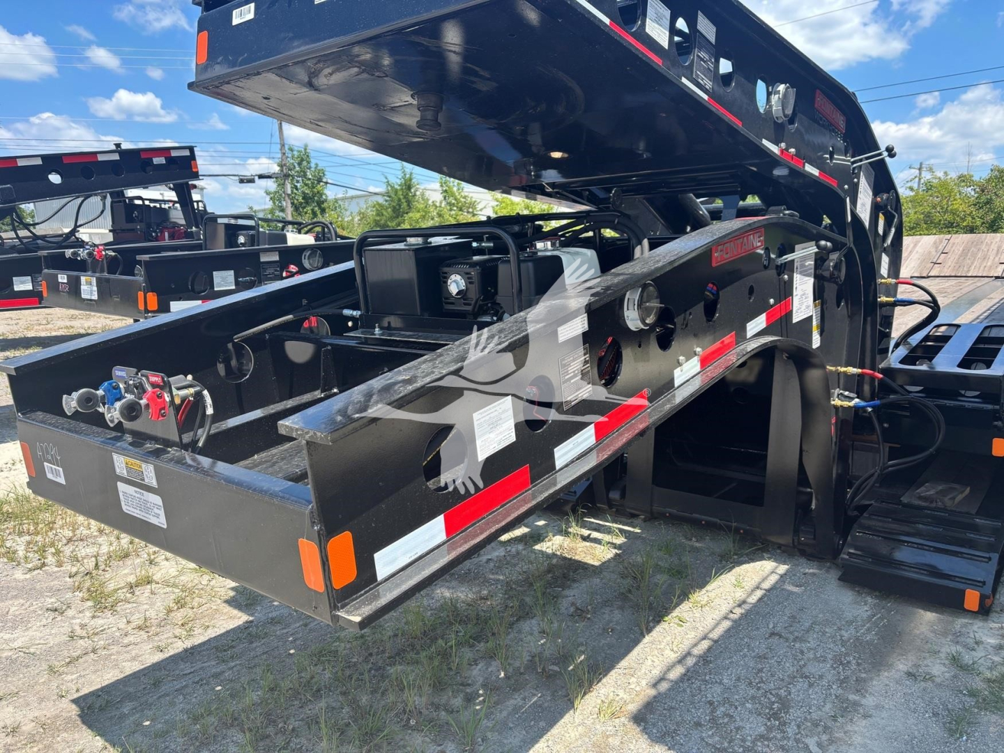 Fontaine Renegade N12 lowboy trailer deck with hydraulic system and control components, tags, and warning decals visible.