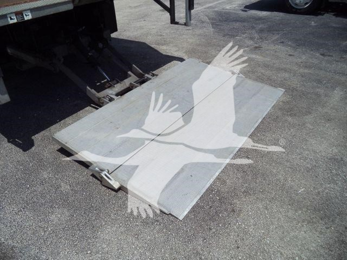 Isuzu NPR-HD truck with lowered cargo ramp/scissor lift plate lying on ground near rear of truck.