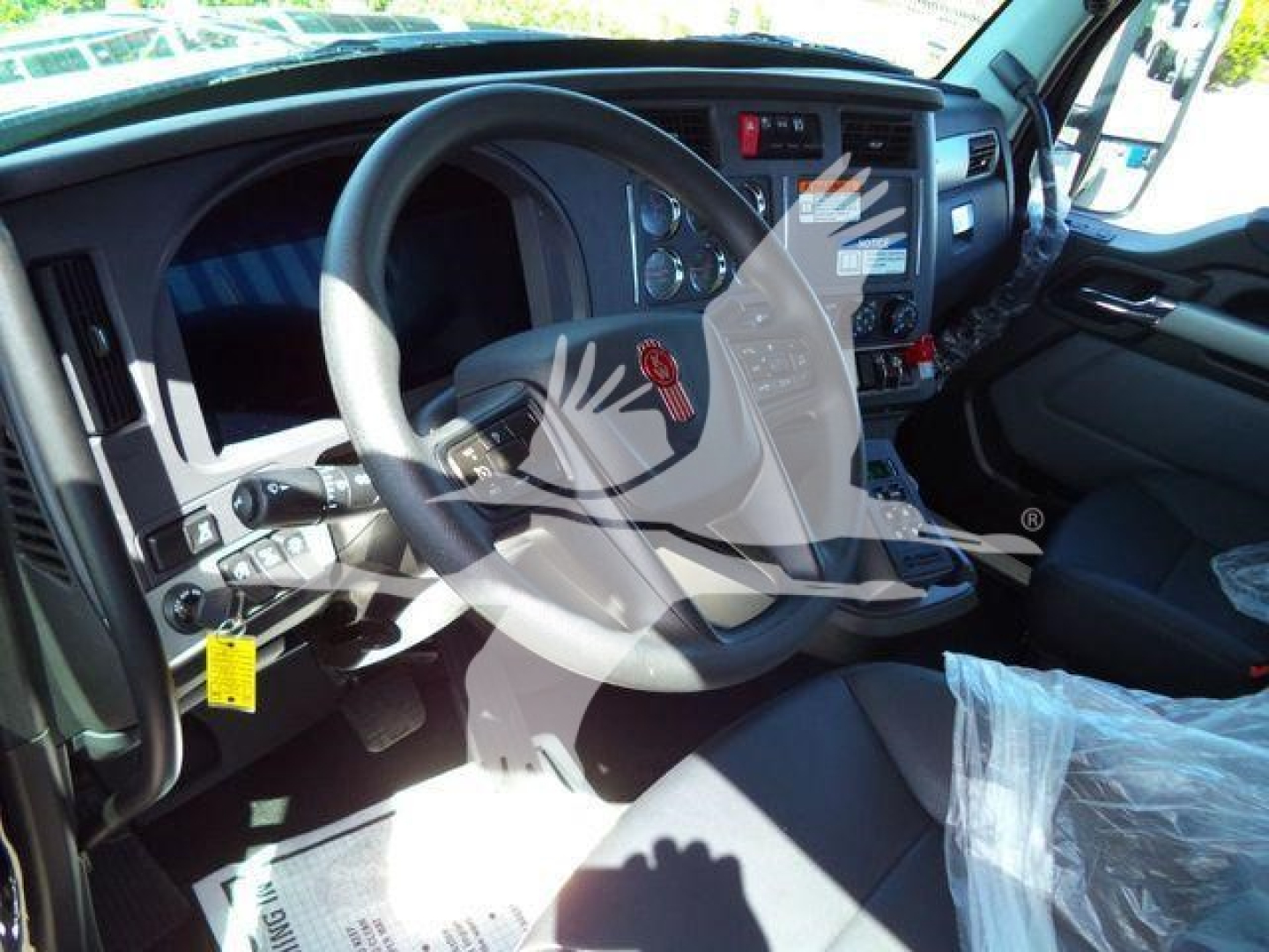 Kenworth T880 cockpit showing steering wheel, dashboard, and driver's seat interior with plastic protective wrap.