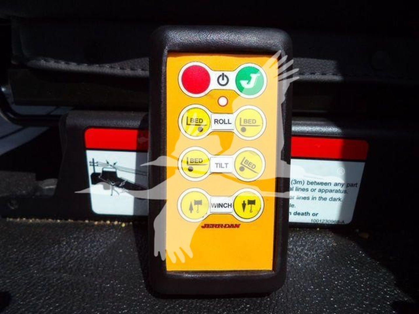 Kenworth truck control pendant with red stop button and green start button showing roll, tilt, and winch indicators.