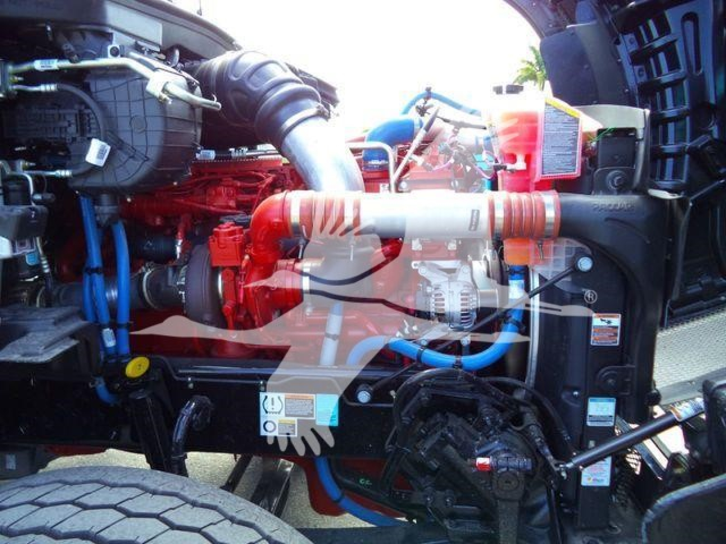 Kenworth T880 engine bay showing red engine, blue and red hoses, and components.