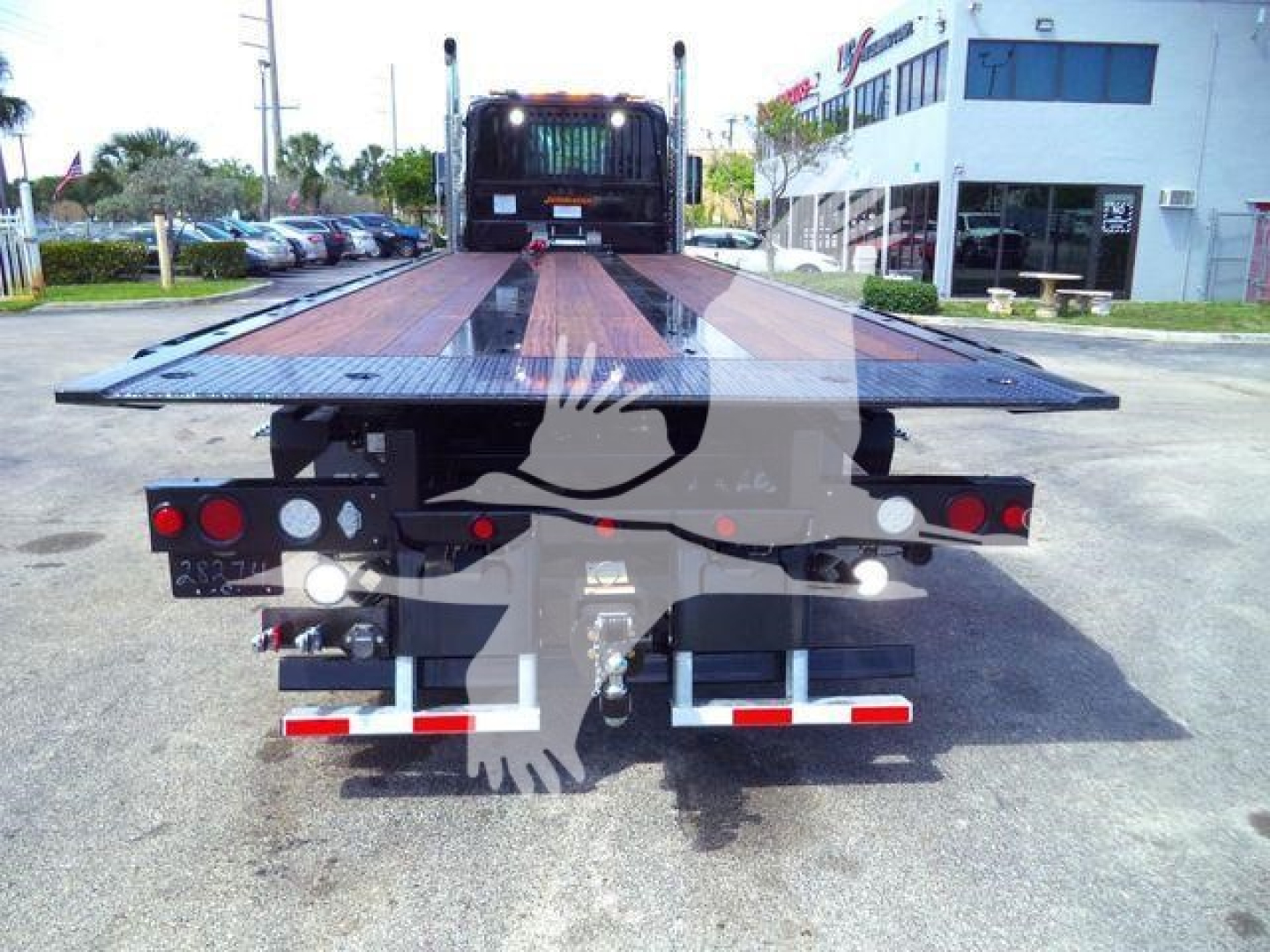 Flatbed tow truck trailer seen from rear, with lights and reflective strips.