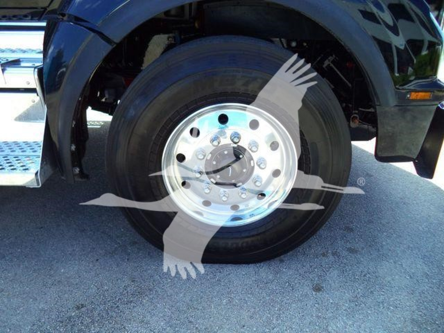 Kenworth T880 front wheel and fender close-up showing steel wheel with multiple lug nuts and tire, front suspension area visible.