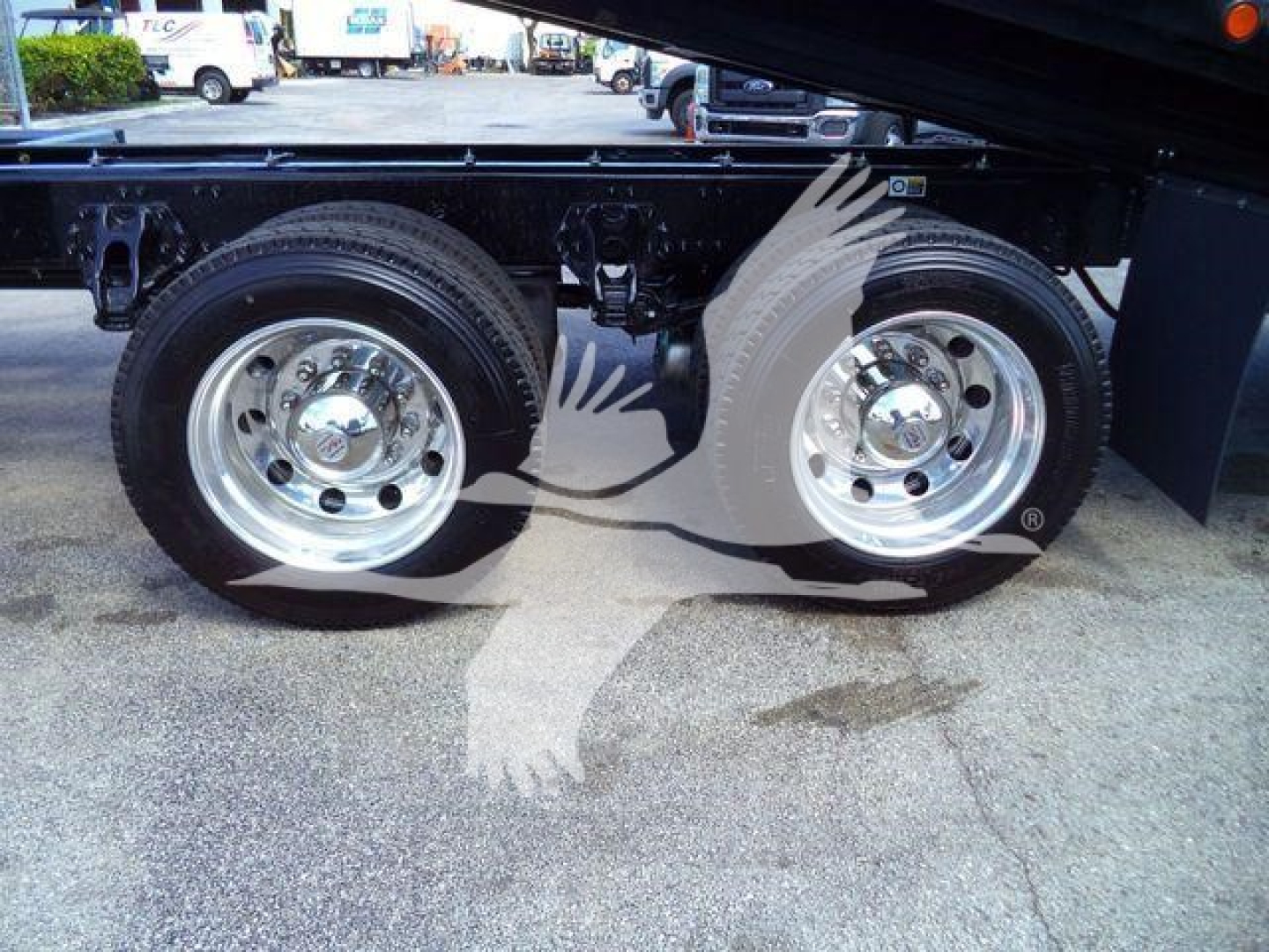 Two Kenworth rear axles with chrome wheels on a new T880 rollback truck, showing dual tires and undercarriage details.