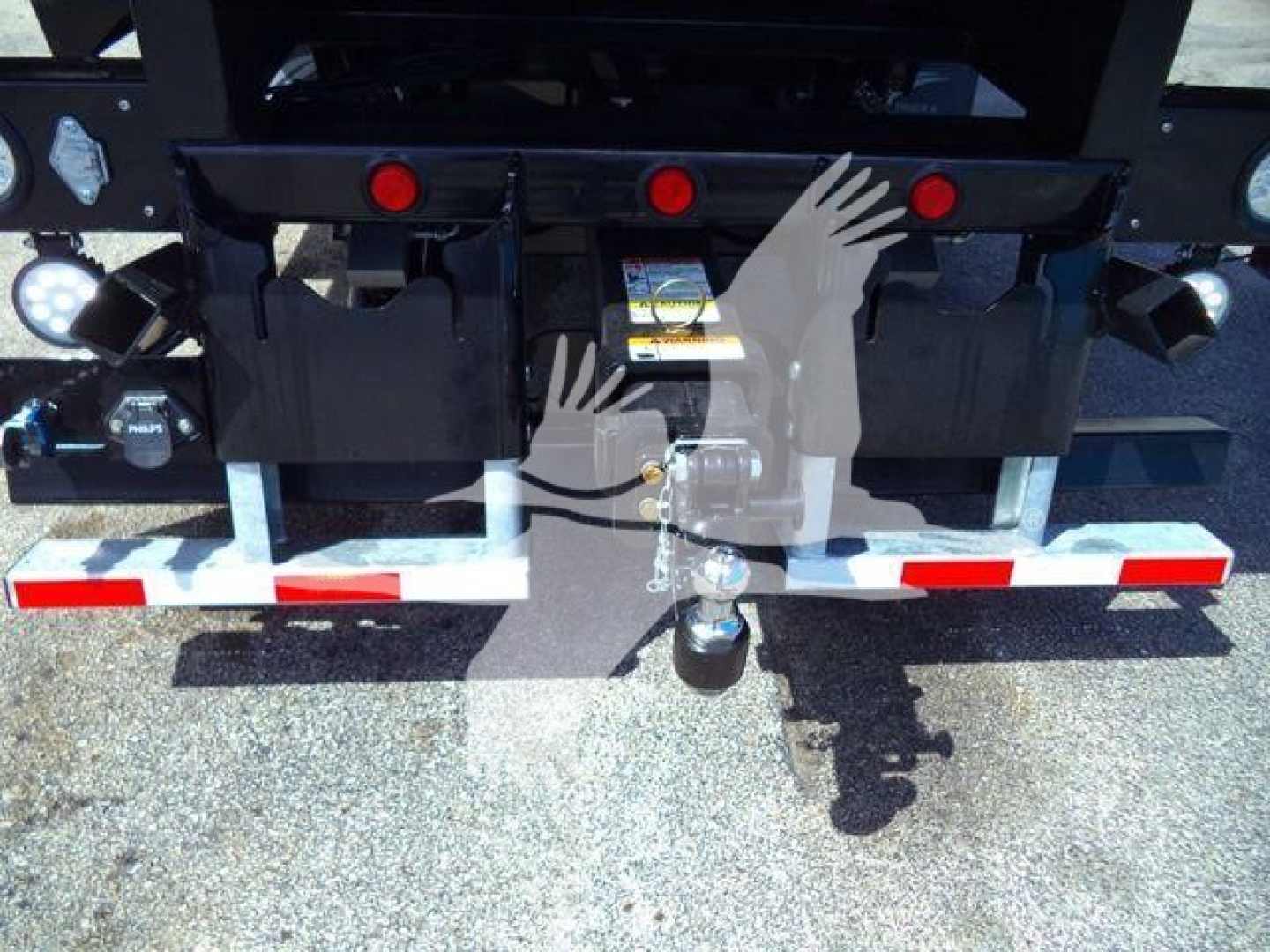 Rear view of a new Kenworth T880 rollback truck showing hitch assembly, trailer gooseneck, safety chains, and taillight area.