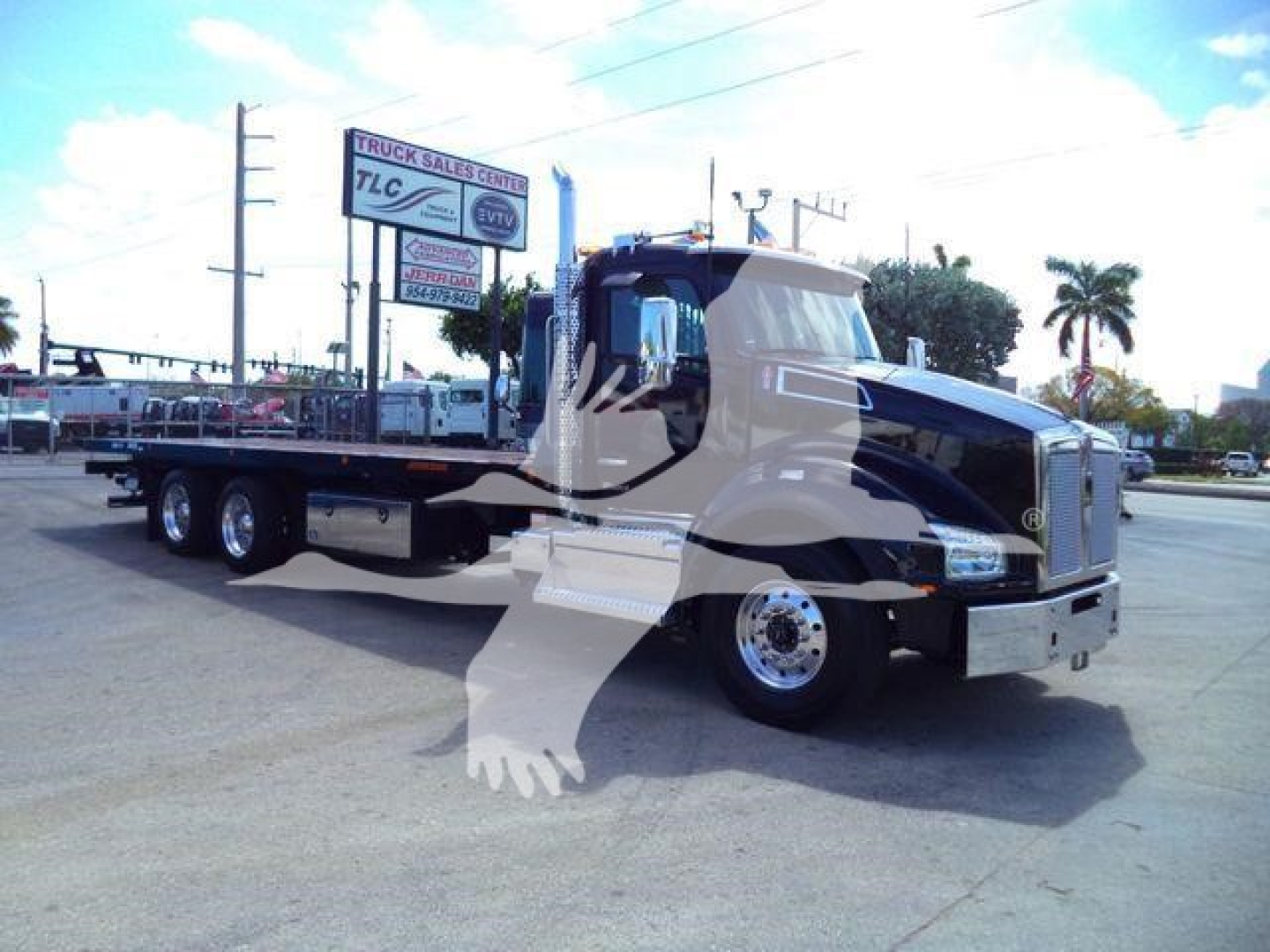 Kenworth T880 rollback truck in black and white color with flatbed, side view showing cab and dual rear axles.
