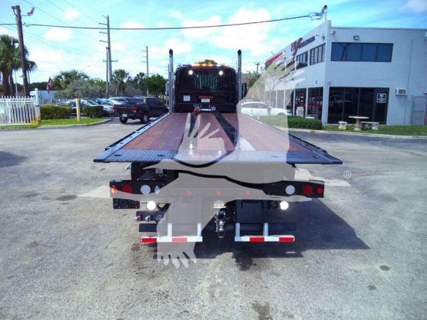 Kenworth T880 rollback truck with flatbed in rear view, loading equipment, with DOT lighting and rear bumper steps.