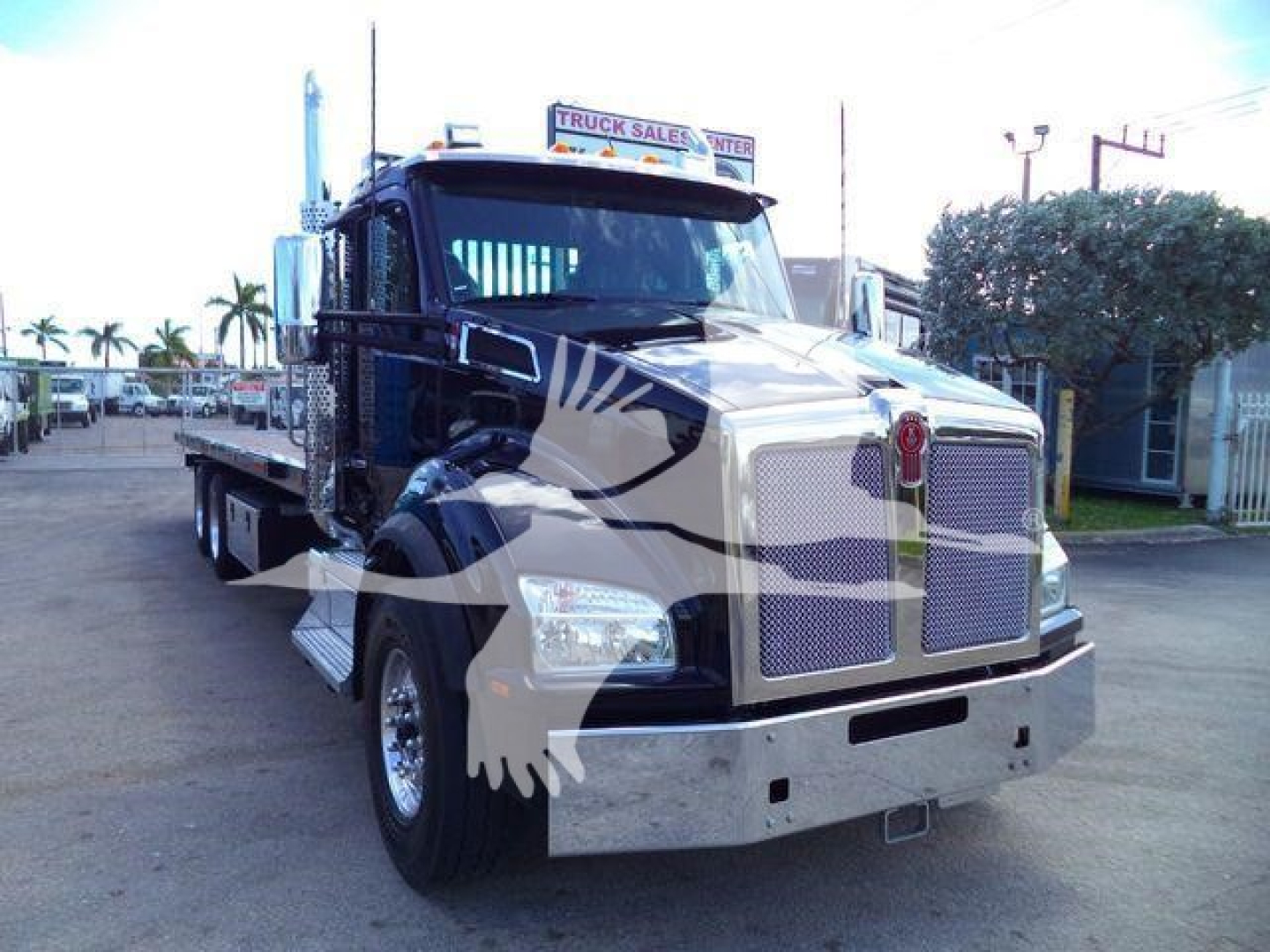 Kenworth T880 front view with rollback heavy-duty truck, chrome grille, large hood, dual headlights, flatbed rear, black and silver color scheme.