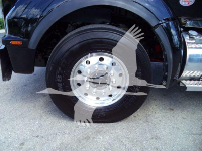Kenworth T880 front wheel and fender view showing silver aluminum wheel and black tire.