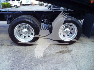 Two Kenworth rear axles with chrome wheels on a new T880 rollback truck, showing dual tires and undercarriage details.