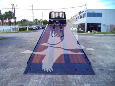 Kenworth T880 rollback bed showing wooden deck and ramp at rear with cabin in distance.