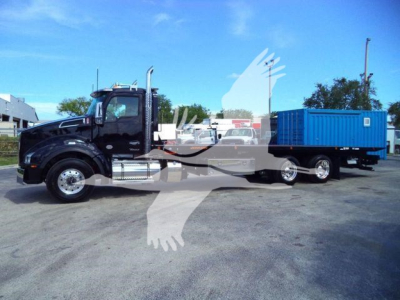 Kenworth T880 rollback truck in black with a blue cargo container on the flatbed, side profile view, dealership lot background.
